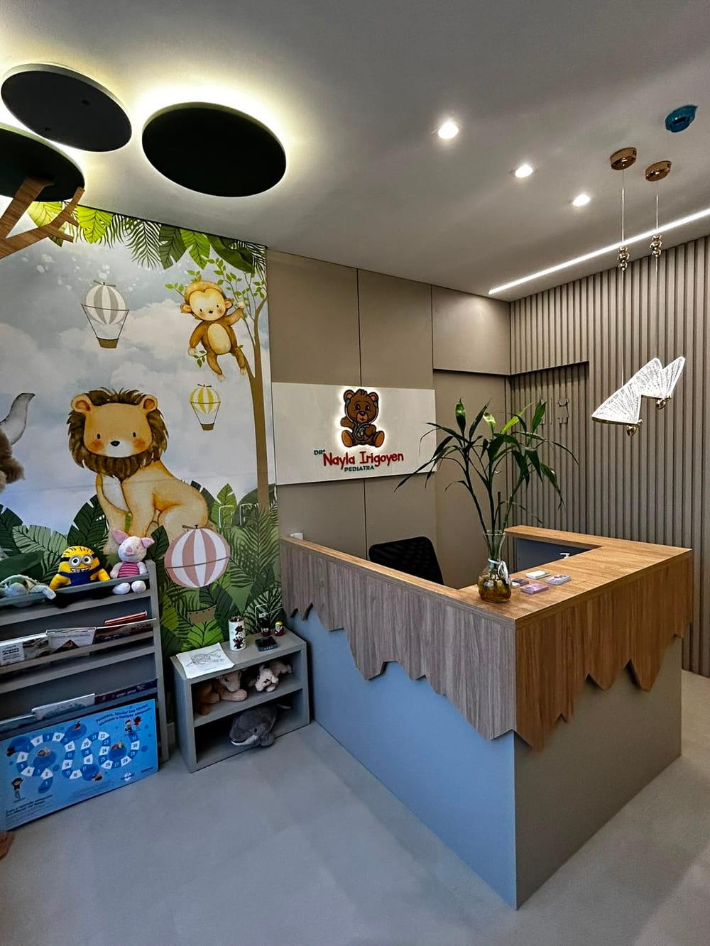 Recepção do consultório da Dra. Nayla Irigoyen, com mural de floresta e brinquedos
